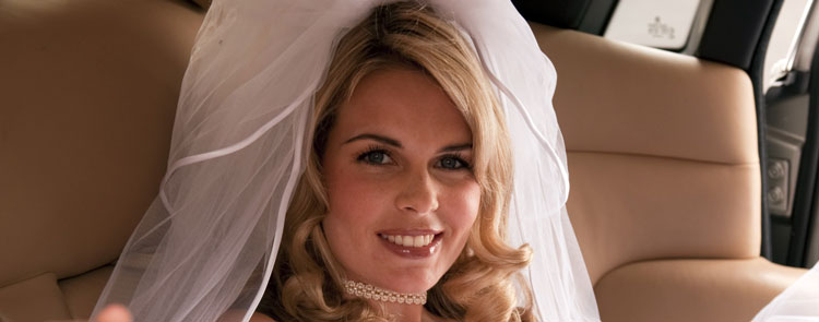 A happy bride reclining on back seat of Rolls-Royce