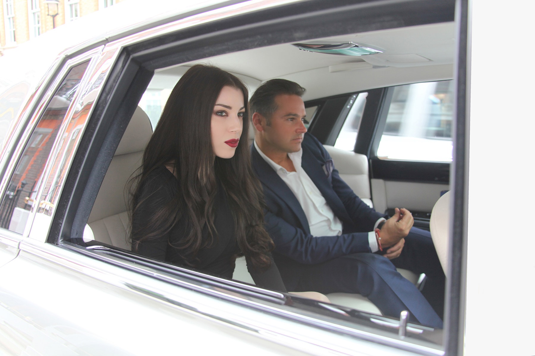 Rear window of chauffeur-driven Rolls-Royce Phantom with 2 passengers on back seat