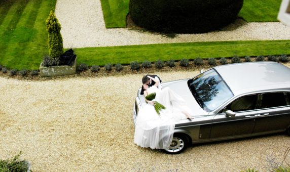 Bride lying over Rolls-Royce Phantom wedding car
