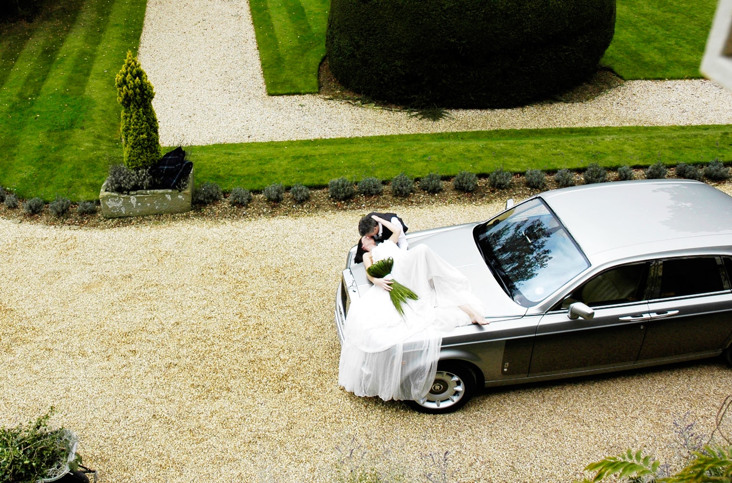 Bride lying over Rolls-Royce Phantom wedding car