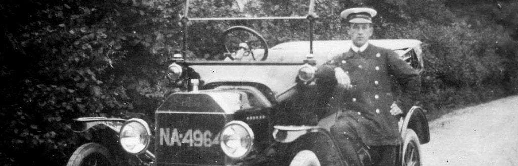 Chauffeur beside vintage car