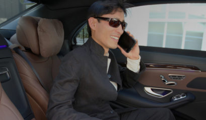 Passenger smiling while on phone in back of Mercedes S-Class chauffeur car
