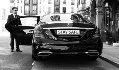 Stay safe number plate on rear of Mercedes S-Class with chauffeur opening the door.