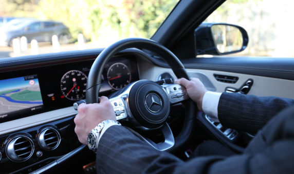 Chauffeur with hands on steering wheel, driving Mercedes-Benz S-Class