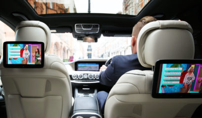 Rear view of chauffeur driving Mercedes S-Class in London. Showing multimedia screens