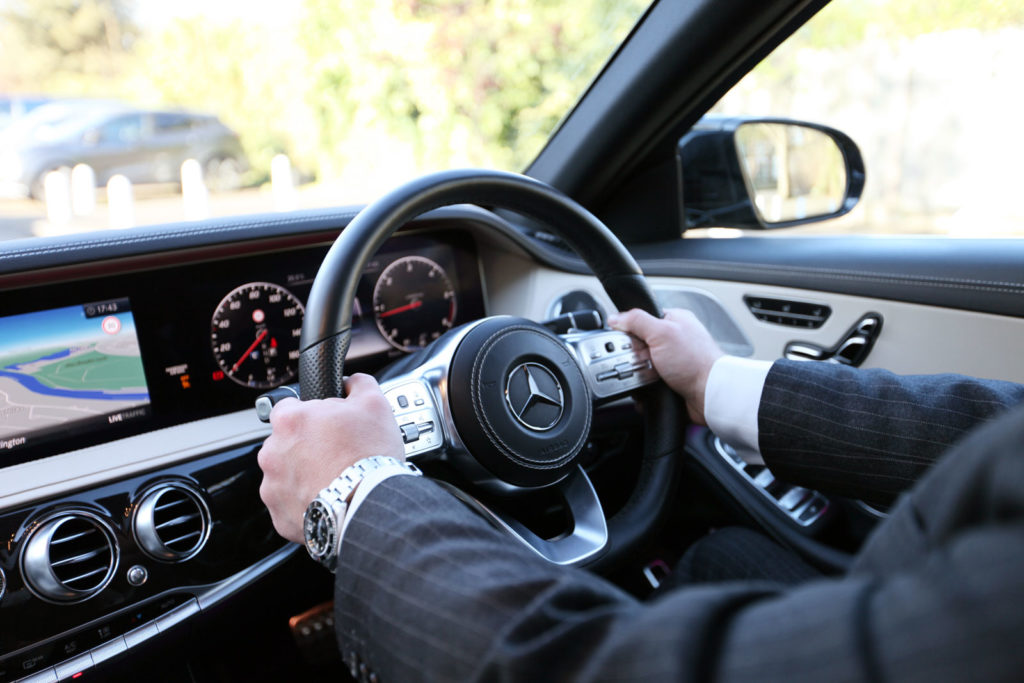 Chauffeur with hands on steering wheel of Mercedes-Benz S-Class limousine