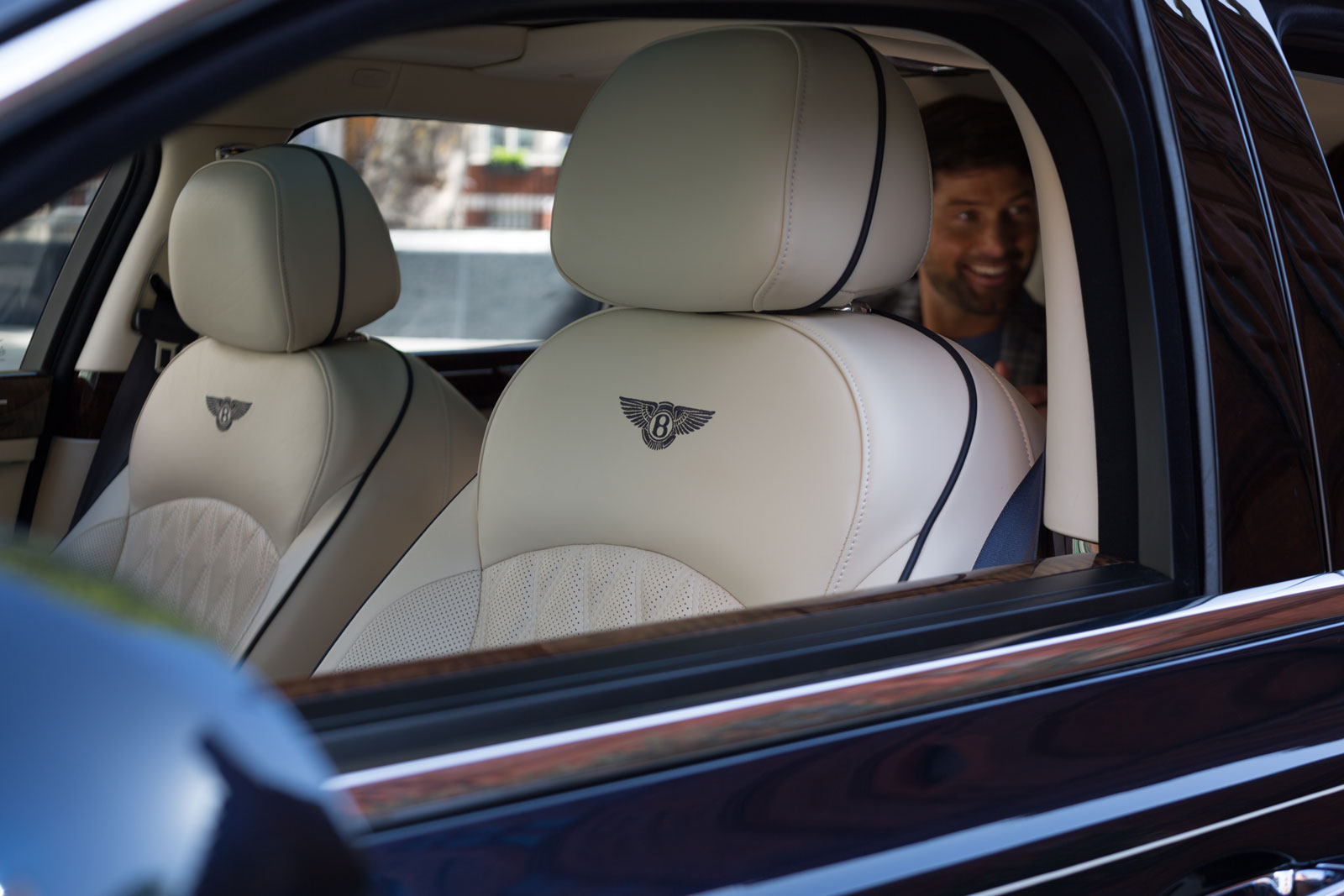 Happy chauffeur passenger in back of Bentley Mulsanne
