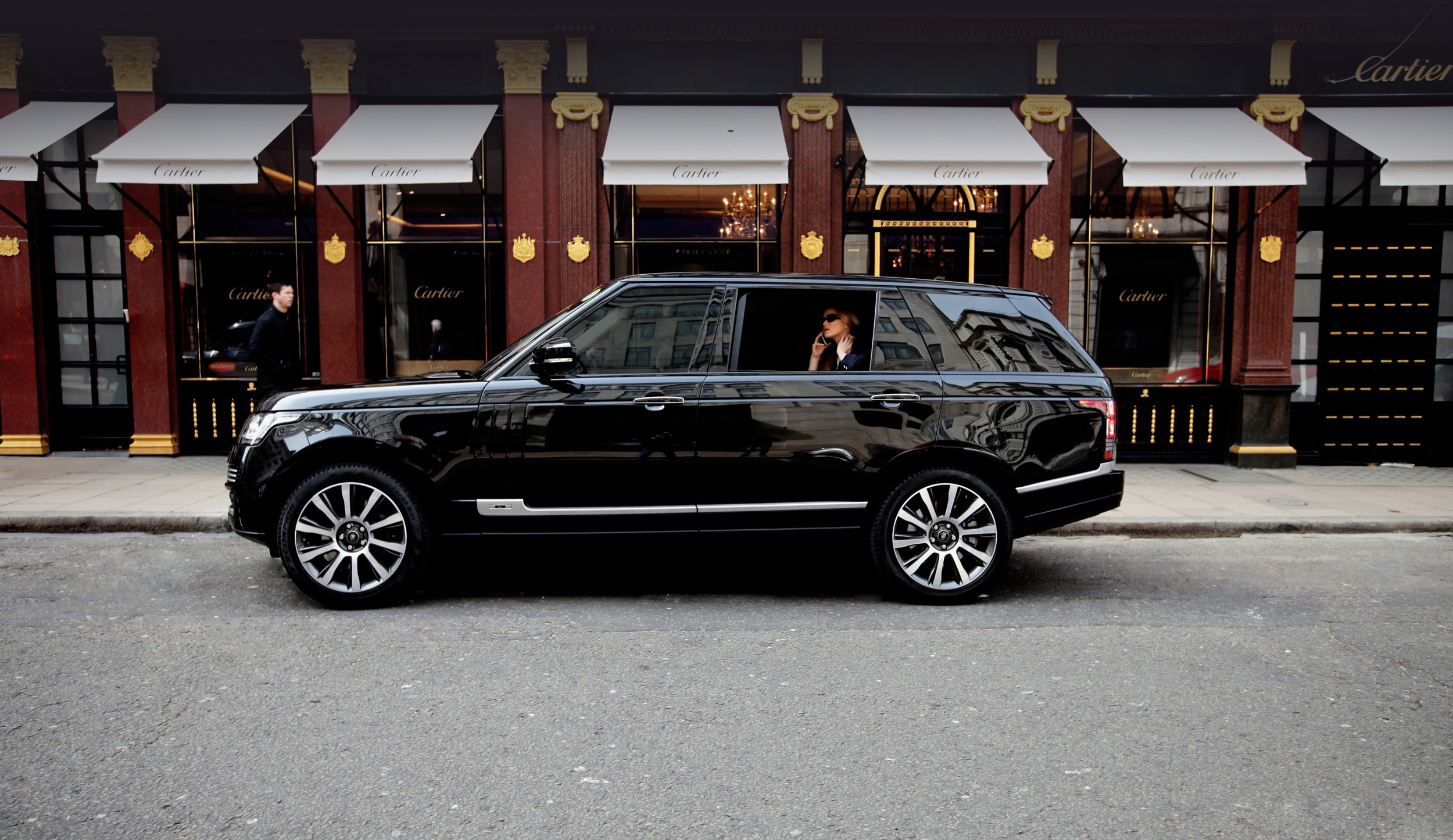 Chauffeur driven Range Rover Hybrid long wheelbase in central London passenger on backseat is on her phone