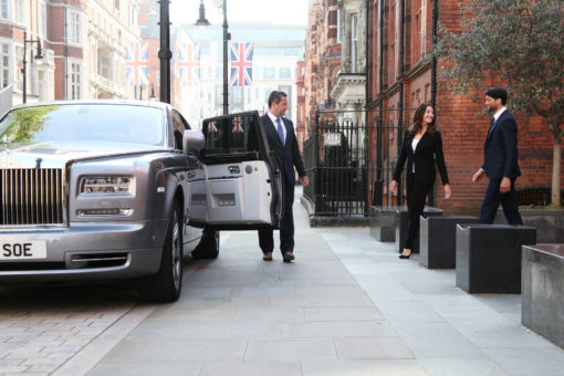 Chauffeur holds door open of Rolls-Royce Phantom as couple approach in London street