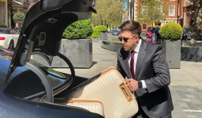 Chauffeur loading luggage into Mercedes S-Class outside Mayfair hotel in London