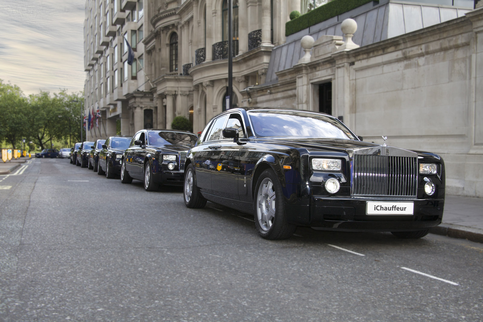 Six black Rolls-Royce Phantom chauffeur cars parked in a line on a London street