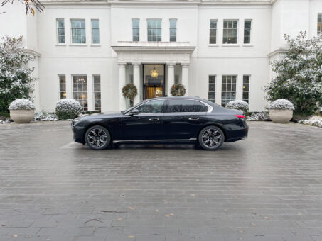 BMW i7 chauffeur car side view in front of Coworth Park hotel in Ascot