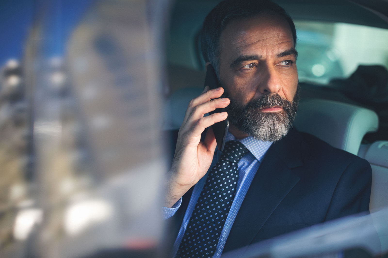 Business man on phone in back of chauffeur car