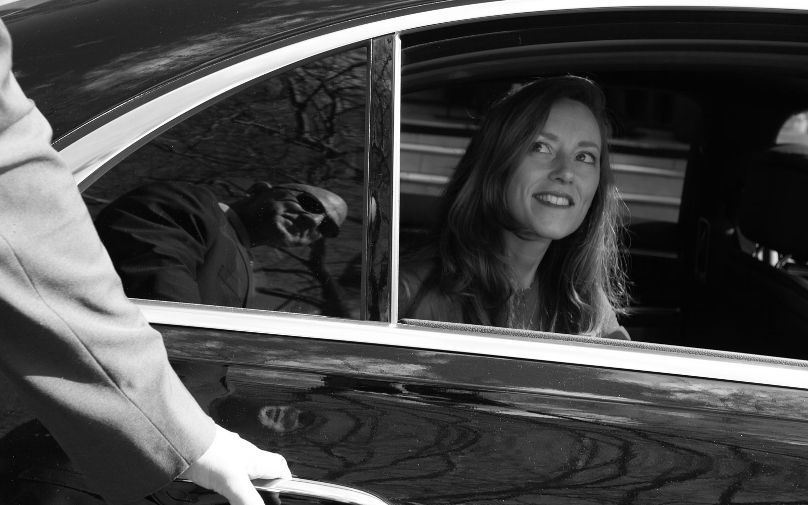 Passenger smiling as chauffeur opens her car door