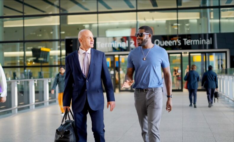Chauffeur walking with passenger at Terminal 2 at Heathrow Airport